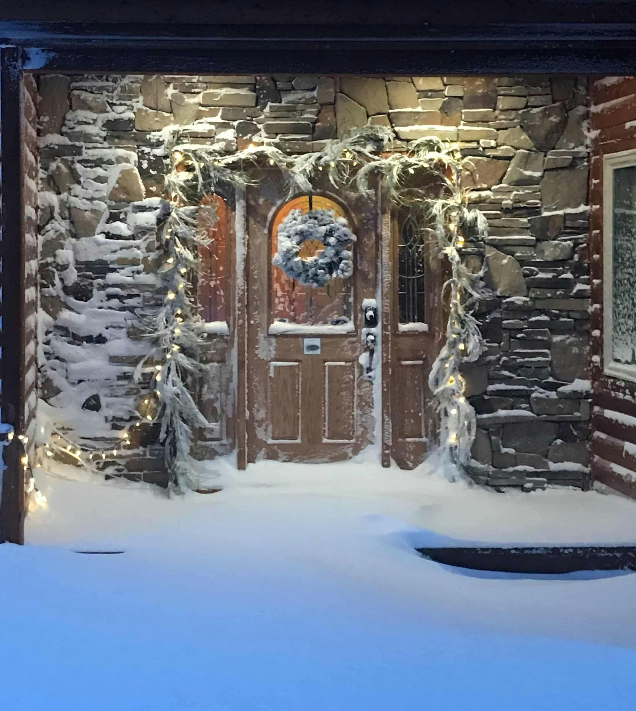 Front door of a home with evergreen bows snow drifts from freshly fallen snow