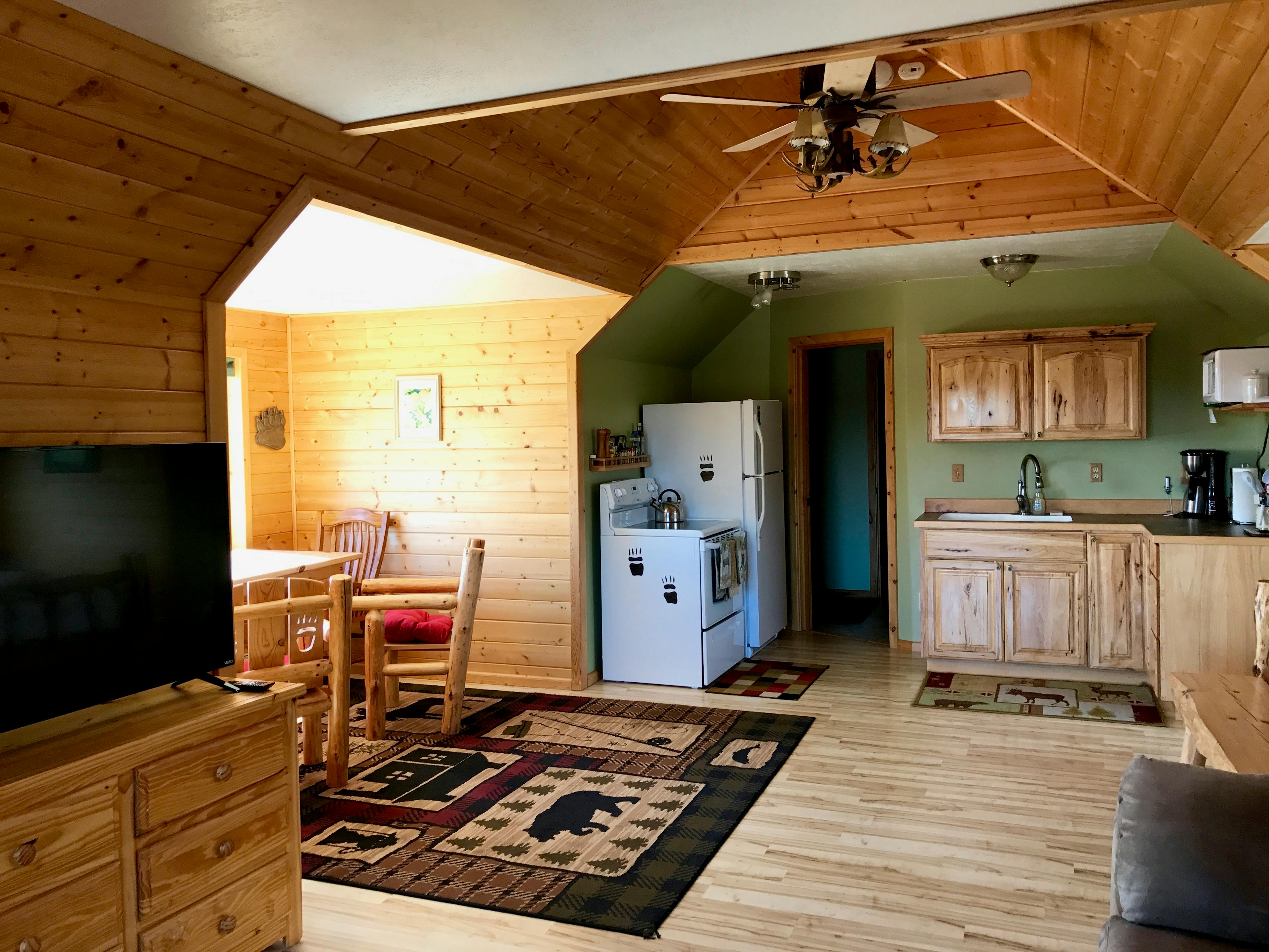 The spacious Bear Paw studio apartment with kitchen area, dining area, bureau with flat-screen TV, and ceiling fan
