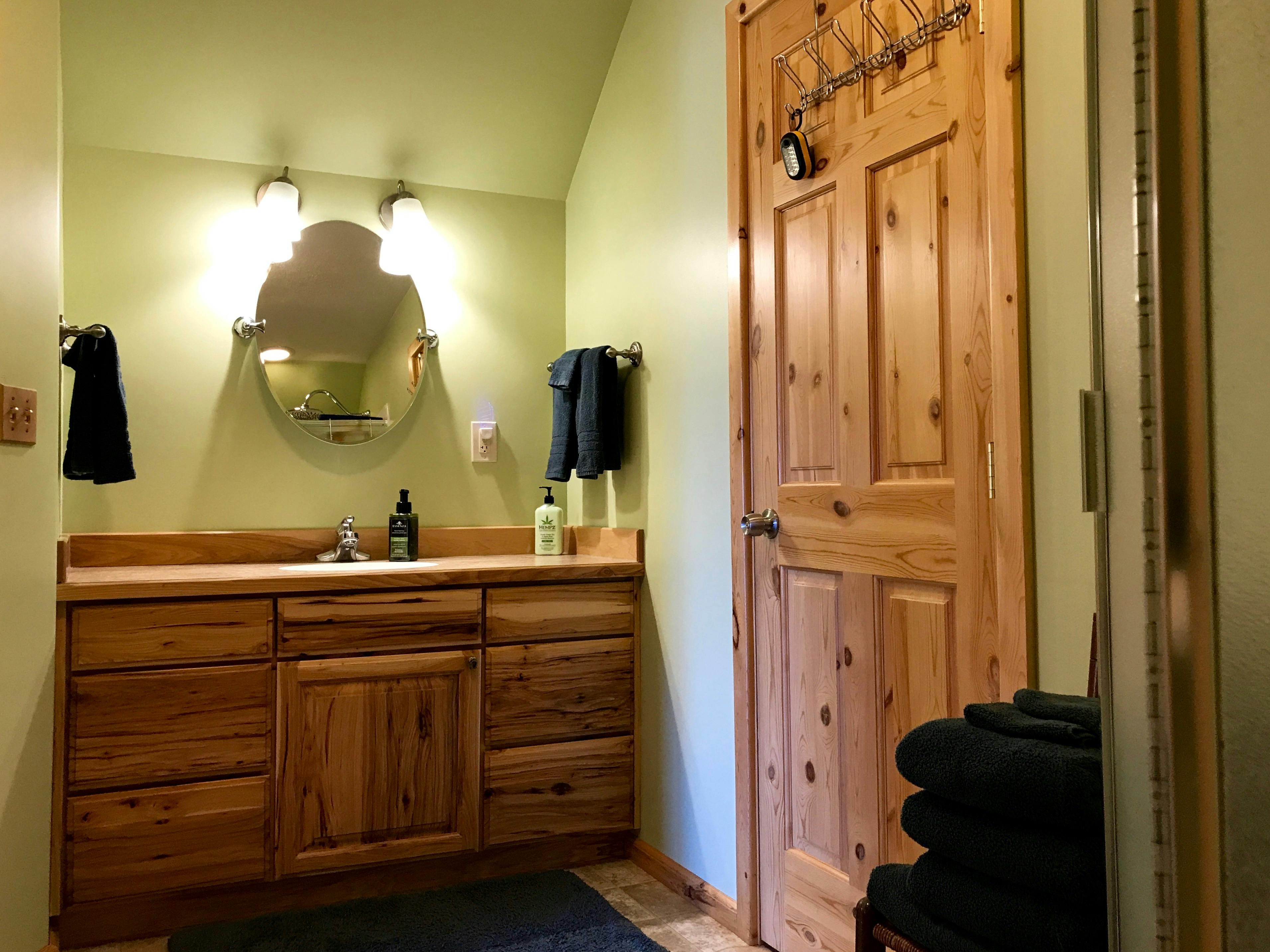 Natural wood bathroom vanity with door leading to big walk in closet