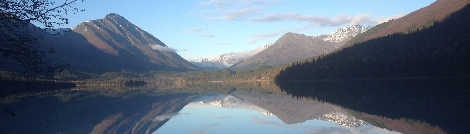 Gorgeous mountain range with snow capped peaks in front of a lake showing the reflection of the mountains