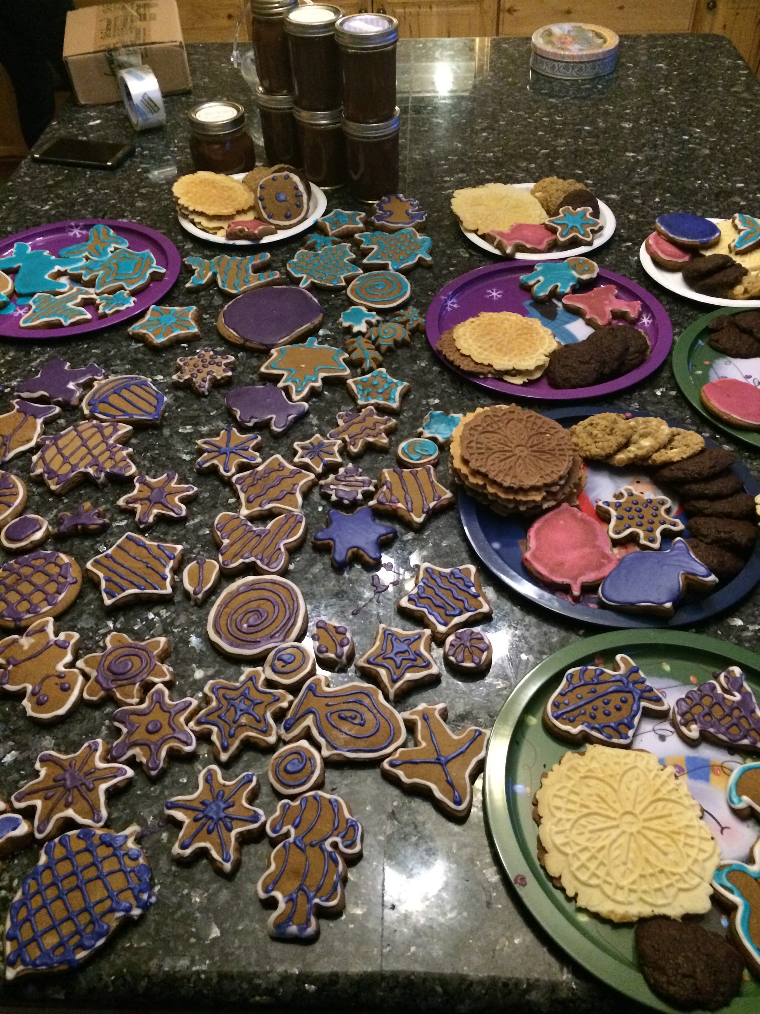 Kitchen table populated with holiday cookies topped with icing