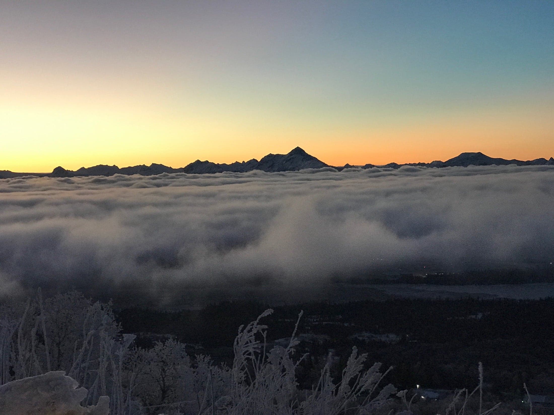 Low clouds and fog hanging over a large valley with mountains in the distance