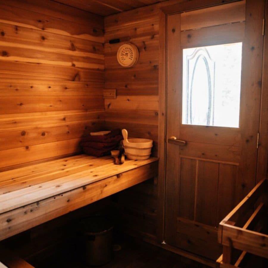 Interior of a sauna with wood walls and bench and door with a large window